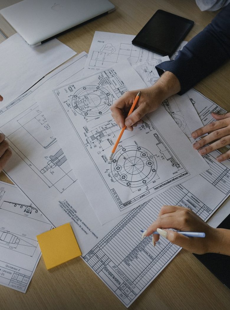 Mãos de consultores analisando diagramas técnicos sobre uma mesa